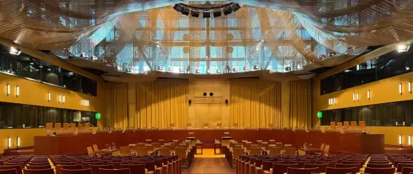 Wnętrze sali sądowej z rzędami drewnianych krzeseł i podwyższonym podium. To miejsce, gdzie zapadają ważne decyzje w izbie kontroli nadzwyczajnej i spraw publicznych.