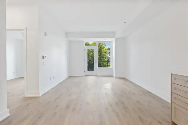 Amplio salón diáfano con suelo de madera clara y puerta acristalada que da a un balcón con vistas a árboles. Ideal para vender piso heredado antes de 5 años.