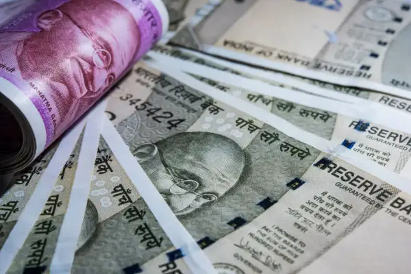 Stos banknotów, w tym fioletowy 2000 rupii i szare 500 rupii, z wizerunkiem Mahatmy Gandhiego. Waluta Indii.