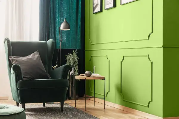 Zielona, aksamitna sofa i zasłony tworzą przytulną atmosferę. Kolor oliwkowy z jakim kolorem pasuje? Zobacz, jak świetnie komponuje się z jaskrawą zielenią ścian.
