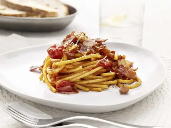En portion pasta amatriciana med tomatsås, bacon och parmesanost.