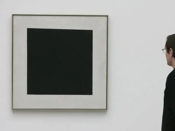 Ein Mann betrachtet ein schwarzes Quadrat auf hellem Grund. Die schlichte Komposition lässt Raum für Interpretationen, die schwarzes Quadrat Bedeutung.
