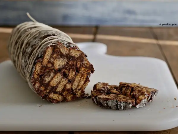 Salame dolce con cacao, un goloso rotolo di biscotti e cioccolato, legato con spago e cosparso di zucchero a velo.