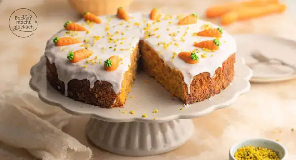 Ein saftiger karottenkuchen mit cremigem frosting, dekoriert mit kleinen Marzipan-Karotten und gehackten Pistazien.