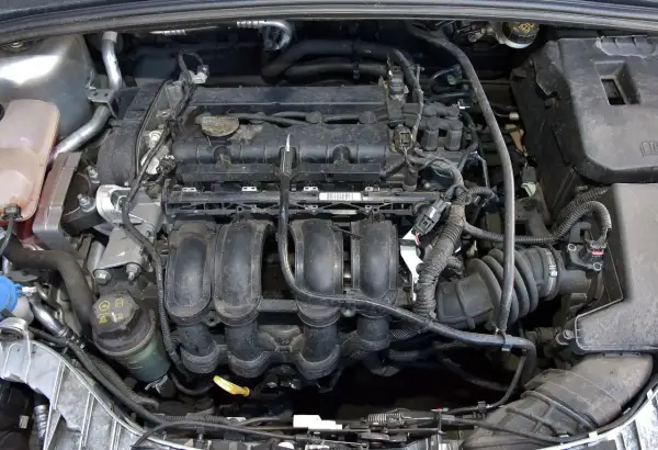 Silnik Ford Focus MK3 1.6 benzyna, widok z góry. Widać kolektor dolotowy, cewki zapłonowe i inne elementy.