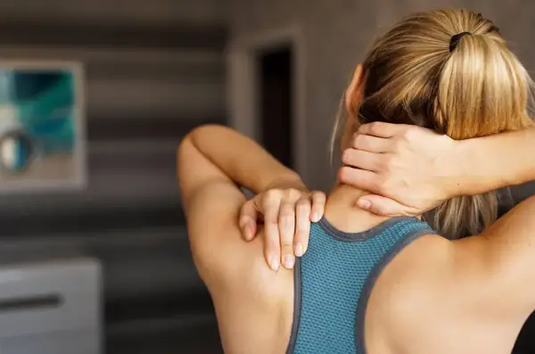 Une coureuse se tient le cou, souffrant d'arthrose cervicale. Ses mains massent la zone douloureuse.