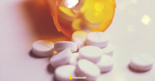 Białe tabletki, w tym lorazepam, wysypują się z pomarańczowego pojemnika.