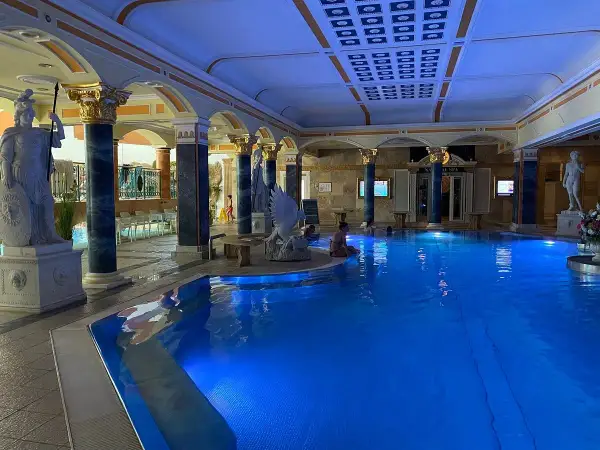 Prunkvoller Innenpool mit blauer Beleuchtung, antiken Statuen und Säulen. Ein Ort der Entspannung in den Teplice Therme.