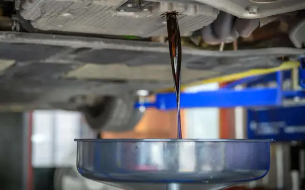 Altöl fließt aus dem Getriebe eines Autos in eine Auffangschale.