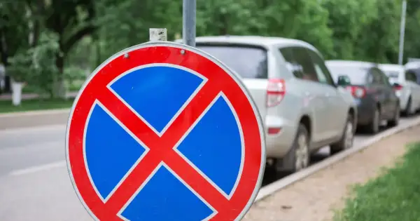 Znak b36 zakazu zatrzymywania się. Samochody stojące w rzędzie na poboczu drogi.