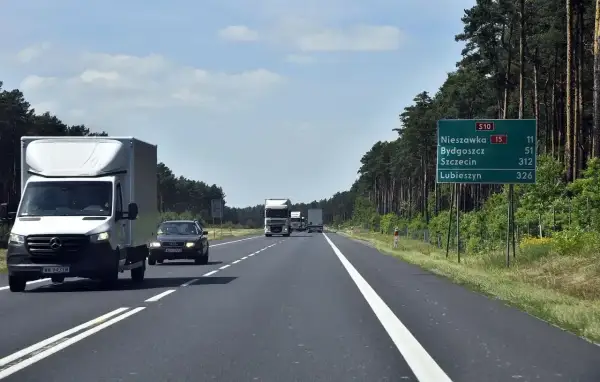 Droga ekspresowa jednojezdniowa S10 wśród lasu. Samochody i ciężarówki jadą w kierunku Nieszawki, Bydgoszczy, Szczecina i Lubieszyna.