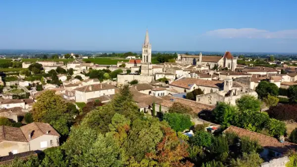 Malowniczy widok na miasteczko Saint-Émilion z charakterystyczną wieżą kościelną i winnicami w tle.