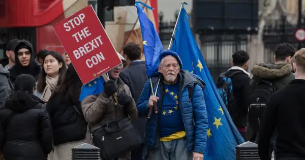 Protestujący w Wielkiej Brytanii z flagami UE i transparentem "Stop the Brexit Con".