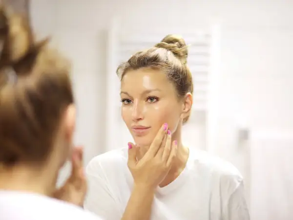 Donna si applica un siero sul viso, chiedendosi quanti sieri si possono usare insieme per una pelle luminosa.