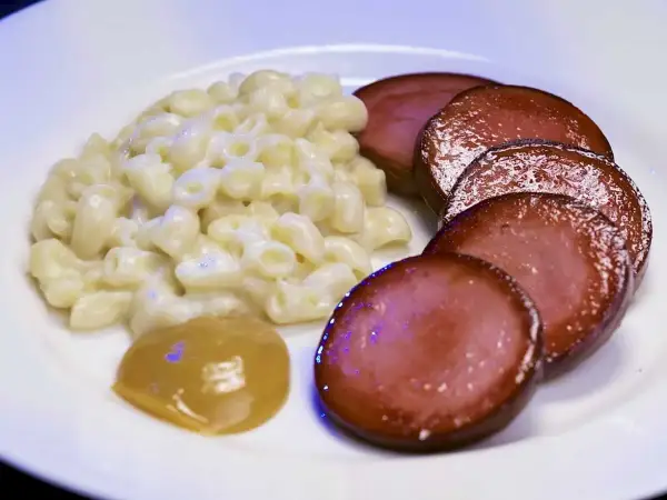 En tallrik med stuvade makaroner, skivad falukorv och en klick senap. En snabb och klassisk svensk måltid.