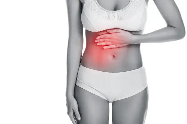 Donna con mano sullo stomaco, evidenziato in rosso. Potrebbe cercare rimedi per il mal di stomaco.