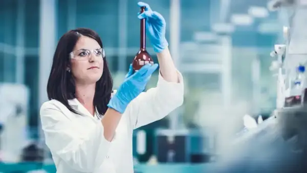 Naukowczyni w laboratorium bada płyn w kolbie. Czy leczenie biologiczne to chemia? Badania naukowe pomagają odpowiedzieć na to pytanie.