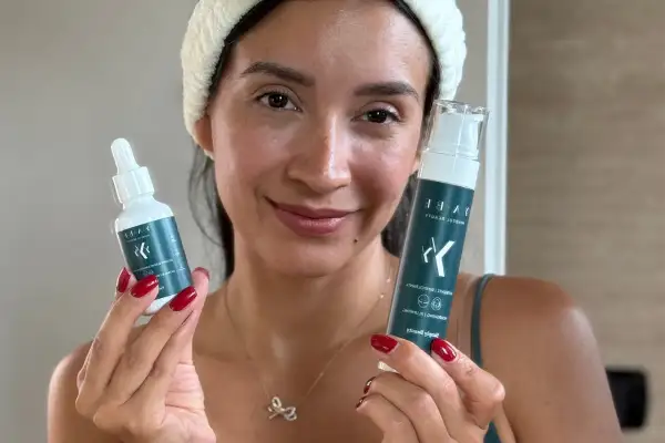 Donna sorridente con prodotti per skincare viso.