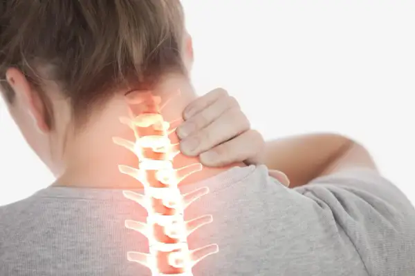 Une personne se tient le cou, montrant une colonne vertébrale cervicale enflammée. La durée de la crise d'arthrose cervicale peut varier.