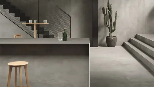Un intérieur moderne avec un escalier, un bar et un cactus. Le sol et les murs sont recouverts d'un élégant carrelage sans joint.