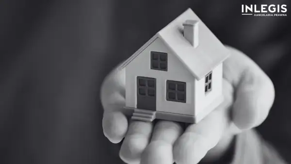 Miniatura domu na dłoni, symbolizująca ograniczone prawa rzeczowe i bezpieczeństwo posiadania.
