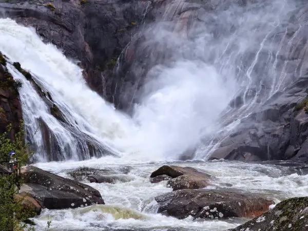 La cascada más grande de Galicia, Ézaro, desciende con fuerza por rocas grises, creando una nube de vapor sobre el río caudaloso.