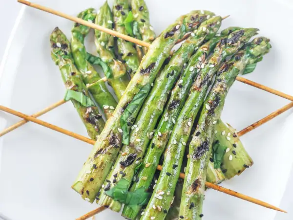 Grillspieße mit Spargel, Sesam und Kräutern auf einem weißen Teller. Perfekt zum Spargel grillen!