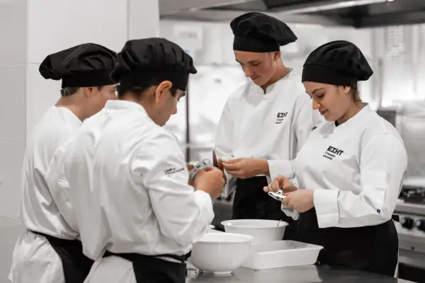 Estudiantes en cursos de cocina para profesionales, concentrados en sus tareas en una cocina profesional.