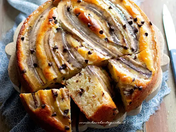 Delizioso dolce con banane mature e gocce di cioccolato, una fetta mostra la morbidezza dell'impasto.