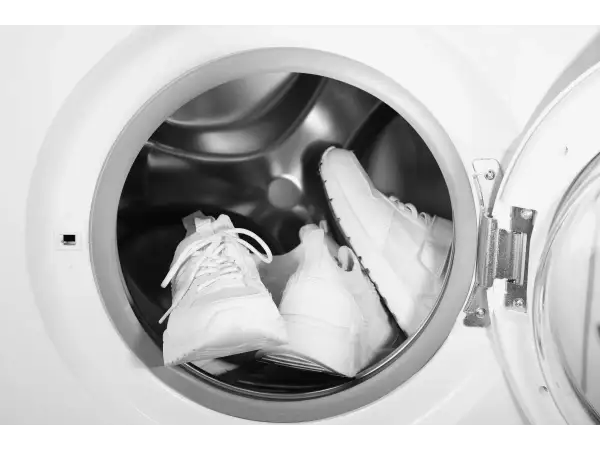 Deux baskets blanches sont prêtes pour leur entretien dans un lave-linge.