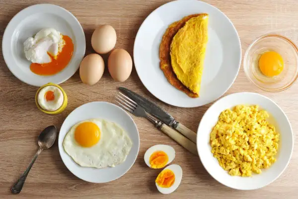 Różne rodzaje jajek na talerzach: jajko sadzone, jajecznica, omlet, jajko w koszulce, gotowane i surowe.
