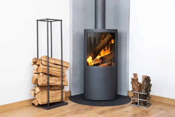 Moderner Kamin mit brennendem Holz. Links Holzstapel, rechts kleiner Holzkorb. Überlegungen zu kamin austauschen kosten sind hier fehl am Platz.