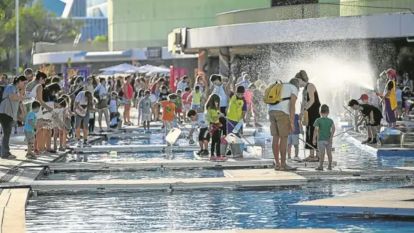 Niños y adultos disfrutan de un **espacio río y juego** con actividades acuáticas bajo el sol.