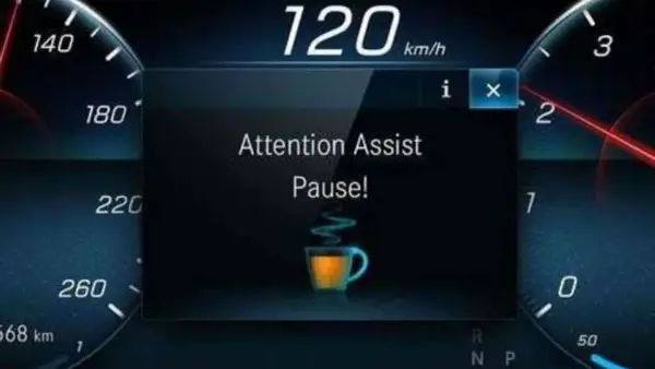 Il display mostra "Attention Assist Pause!" con una tazzina di caffè, indicando come funziona il rilevatore di stanchezza Volkswagen: suggerisce una pausa.