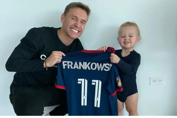 Frankowski piłkarz z synkiem prezentuje koszulkę z numerem 11.