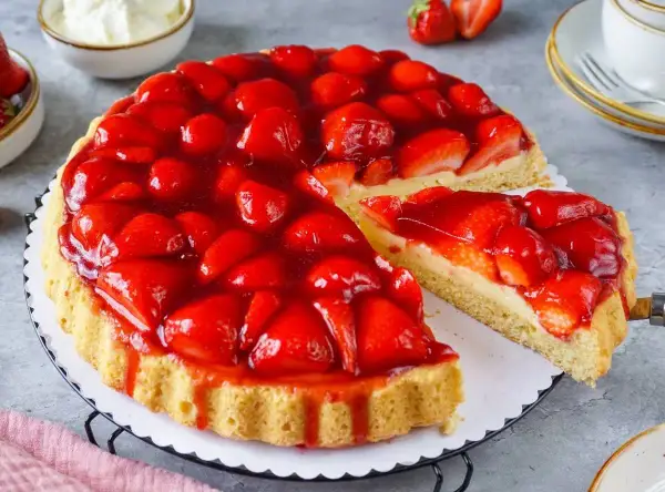 Eine saftige Erdbeertorte mit frischen Erdbeeren und Tortenguss, ein Stück wird herausgeschnitten.