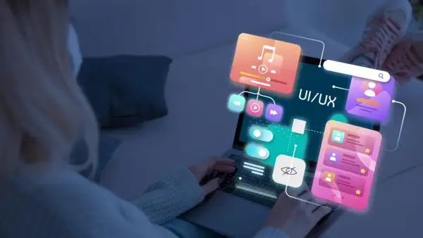 Persona trabajando en el diseño web de una aplicación, con elementos de UI/UX flotando sobre la pantalla.