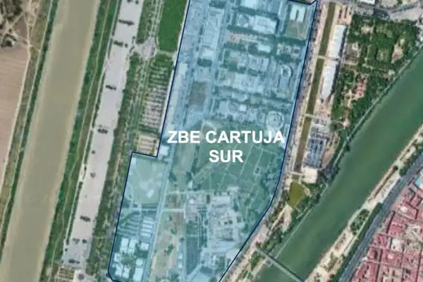 Vista aérea de la zona ZBE Cartuja Sur en Sevilla, delimitada en azul, junto a un río y edificios.