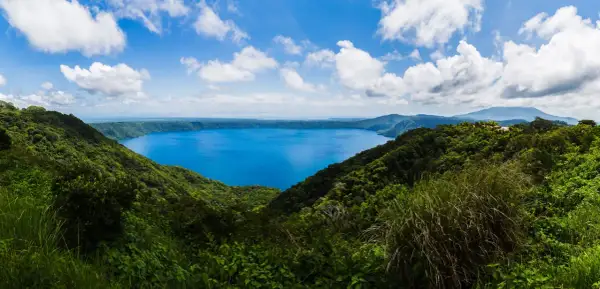 Vista panorámica de un lago azul intenso rodeado de vegetación exuberante y montañas. Un destino imperdible que ver en Nicaragua.