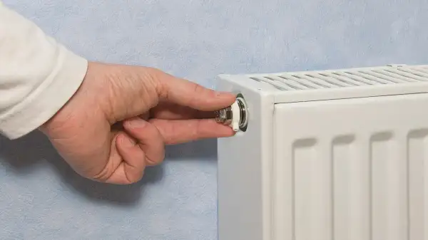 Mano che gira la valvola di uno spurgo termosifone. È il momento di capire quando spurgare i termosifoni per un riscaldamento efficiente.