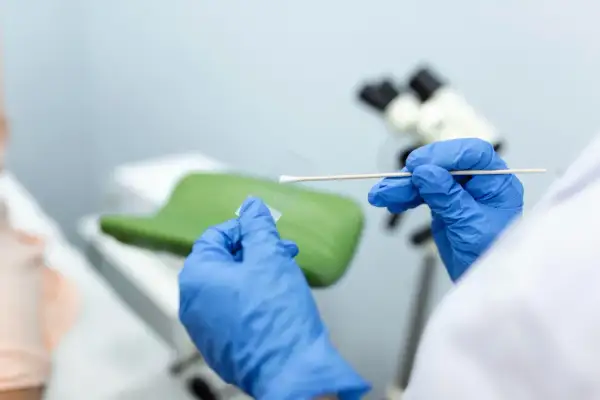 Ręce w niebieskich rękawiczkach przygotowują próbkę do analizy. Wynik biopsji tarczycy kategoria 3 jest kluczowy dla dalszego leczenia.