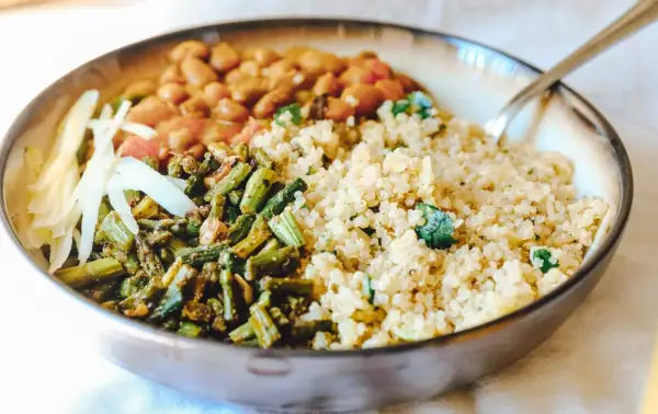 Gesundes Gericht mit Quinoa, Bohnen, grünem Gemüse und Kohlstreifen in einer Schüssel.