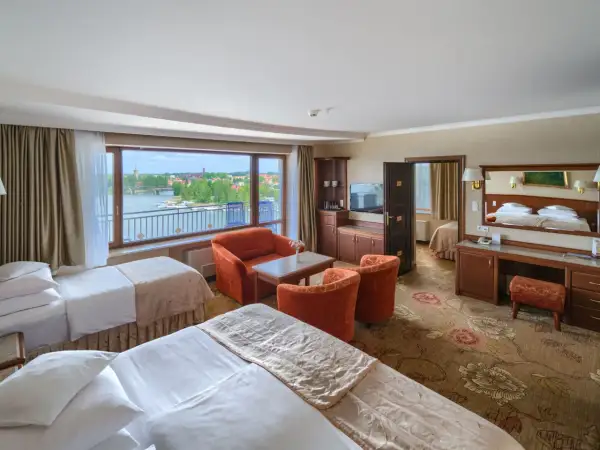 Pokój hotelowy z dwoma łóżkami, widokiem na jezioro i meblami wypoczynkowymi.