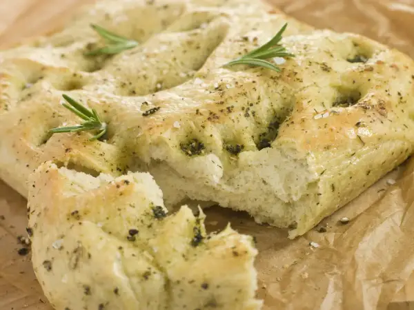 Frisch gebackene italienische Focaccia mit Rosmarin und grobem Salz, auf Backpapier.