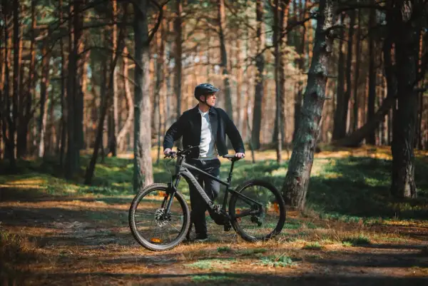 Mężczyzna z rowerem w lesie, gotowy na odkrywanie tras rowerowych Łeba.