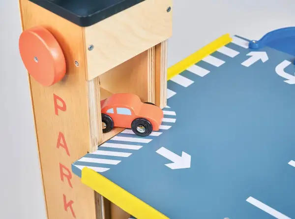 Drewniany parking na autka z pomarańczowym samochodzikiem wjeżdżającym na rampę.