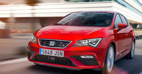 Czerwony Seat Leon 2025 pędzi po drodze, jego sportowy design przyciąga wzrok.