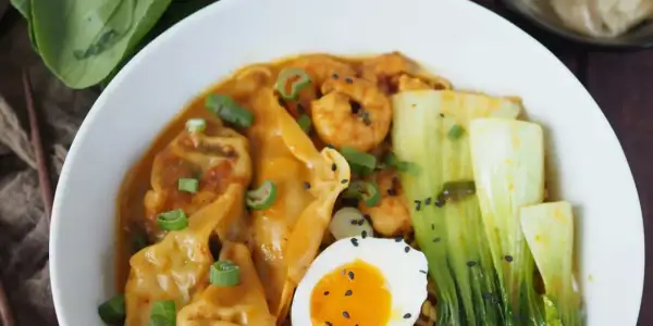 Schüssel mit Ramen, Garnelen, Gyoza, Pak Choi, Ei und Frühlingszwiebeln. Köstliche Ramen-Toppings!