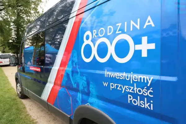 Niebieski van z napisem "Rodzina 800+" i hasłem "Inwestujemy w przyszłość Polski". Widoczne sylwetki rodziny.