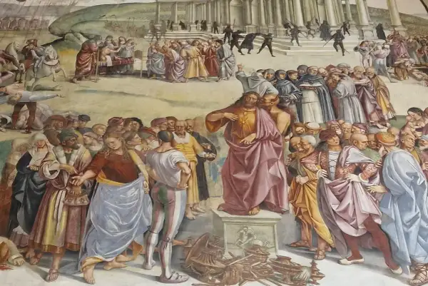 Judasz całuje Jezusa, zdradzając go. Tłum ludzi, w tym mnisi i żołnierze, obserwuje scenę. W tle widać budynek i chaos.